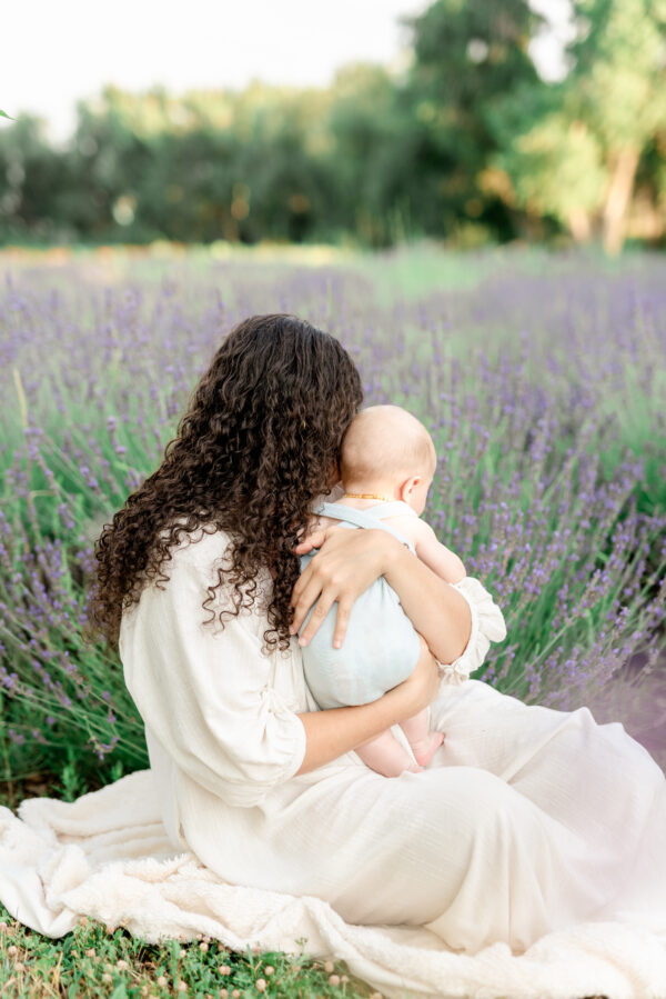mother and baby sit in a field of lavender blooms