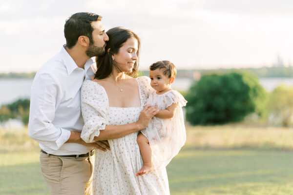 Dad kisses mom during a field family session in Dallas