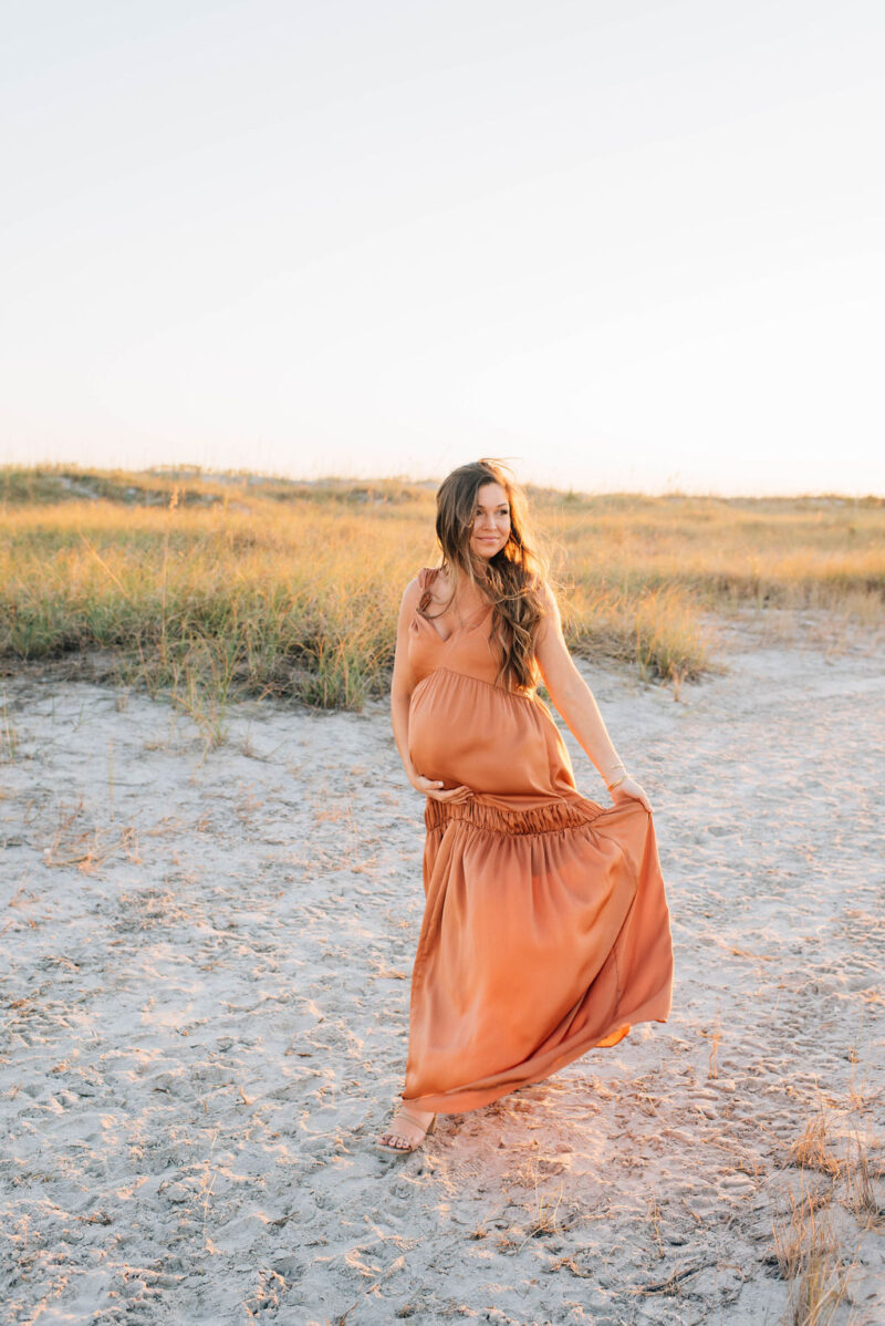 pregnant mama walking on the beach at sunset photographed by Chelsea Hollis in Wilmington, NC