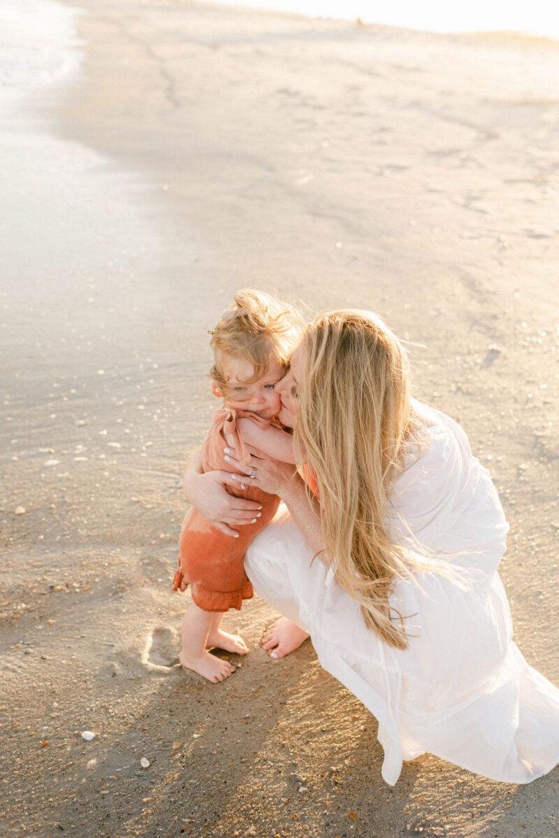 mama and baby hugging on the beach at sunset photographed by Chelsea Hollis in Wilmington, NC