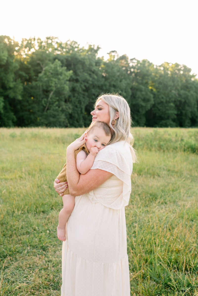 mom and baby in a field at sunset photographed by Chelsea Hollis in Wilmington, NC