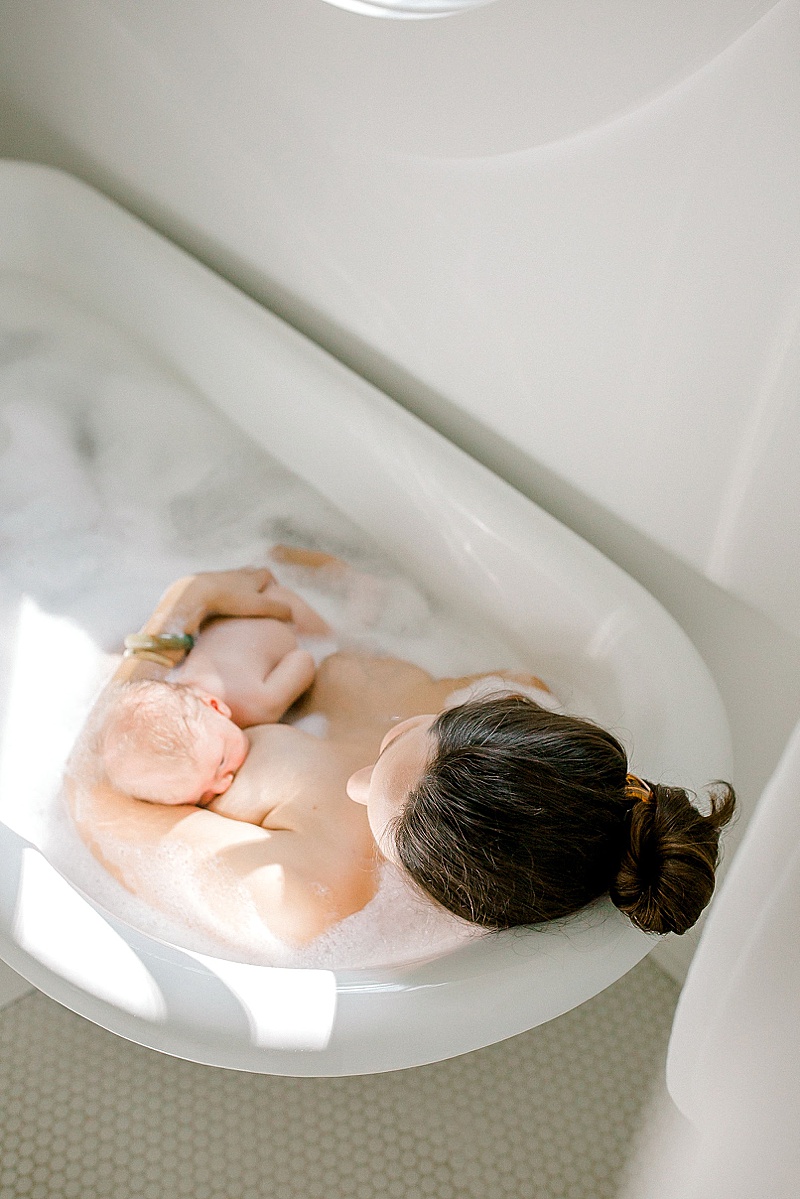 intimate newborn photography session in Richmond Virginia mama and baby nursing in the bathtub featured by the motherhood anthology