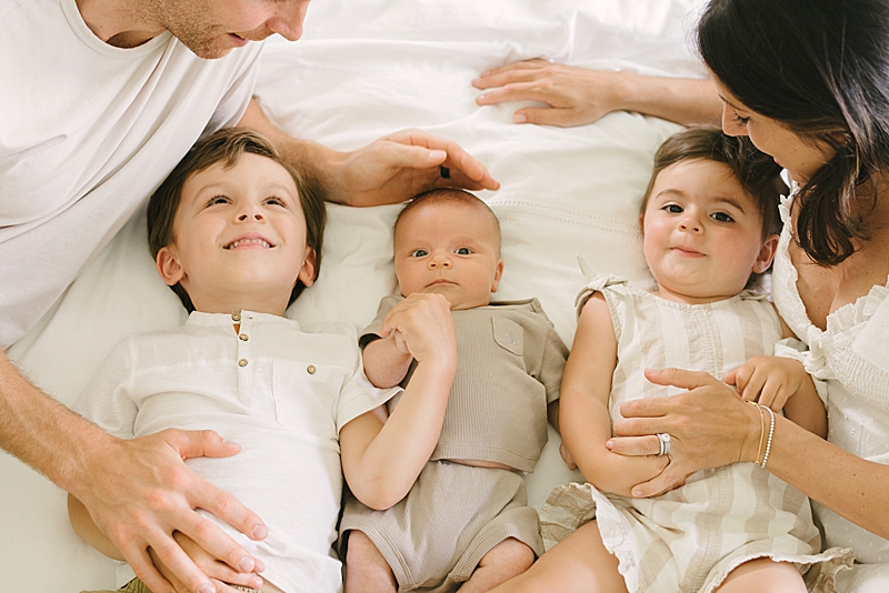 cozy in-home newborn session neutral tones family photography boca raton fl nkb photo featured on the motherhood anthology family on the bed natural light photography